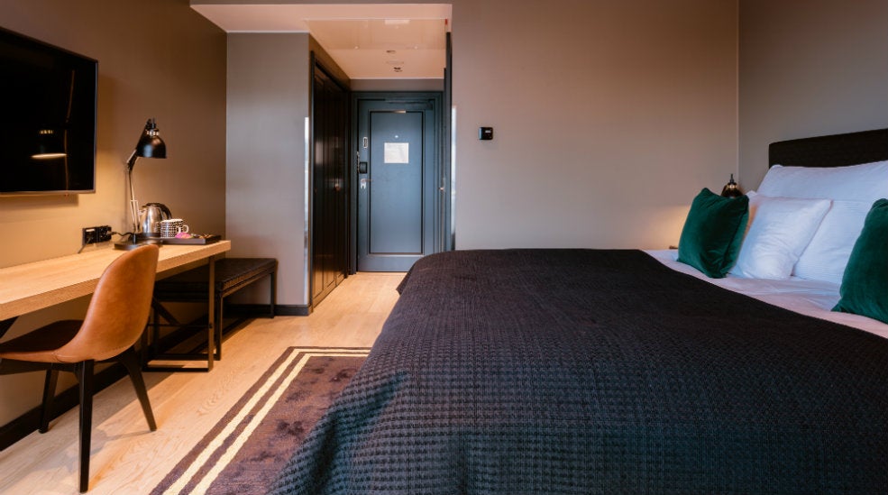 Double bed with a grey bedspread, workspace, chair and TV in a standard double room at the Clarion Hotel Helsinki Airport