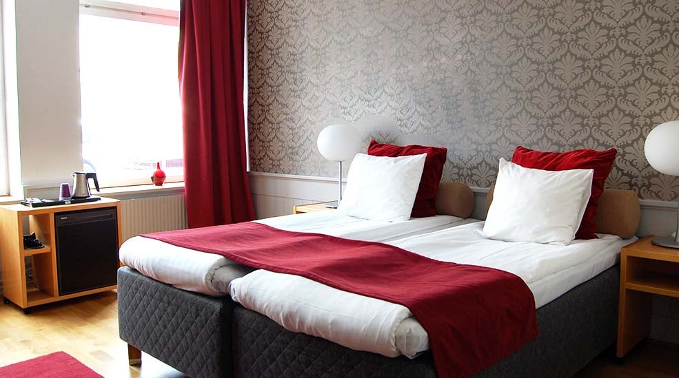 Family room with double bed and bedside lamps with minibar at Clarion Collection Hotel Bolinder Munktell Eskilstuna